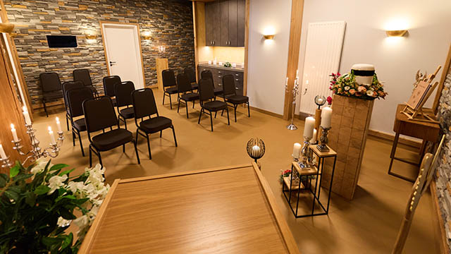 Trauerhalle Versmold – Blick vom Rednerpult auf Bestuhlung Innenansicht der Trauerhalle von Schwarz & Sohn in Versmold: Blick vom Rednerpult auf Bestuhlung, Urnenpodest und Kerzenständer.